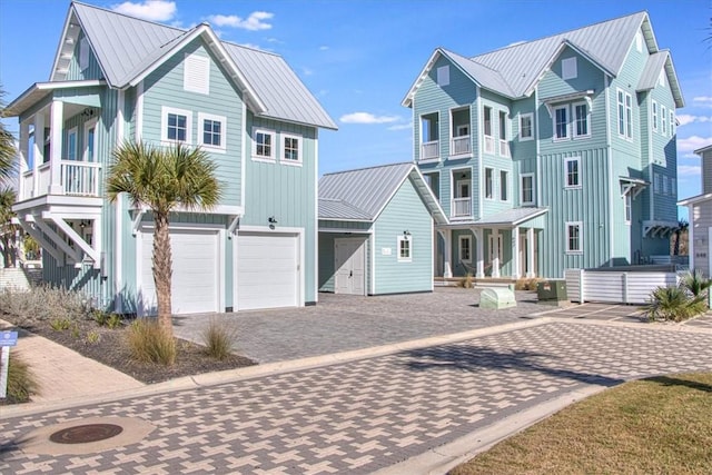 view of front of home featuring metal roof, an attached garage, covered porch, board and batten siding, and a standing seam roof