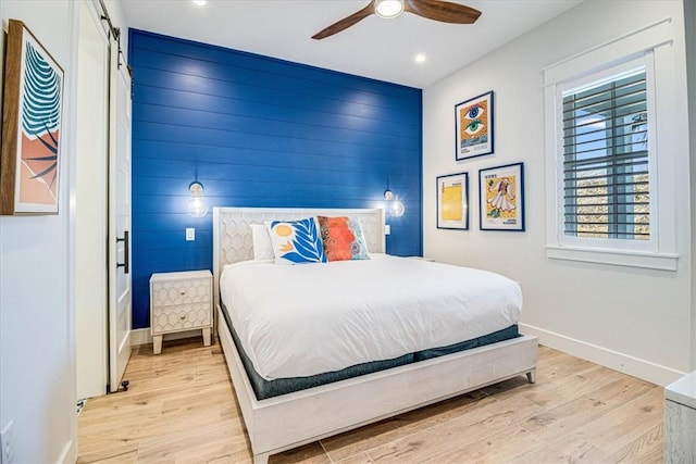 bedroom featuring recessed lighting, light wood-style flooring, an accent wall, ceiling fan, and baseboards