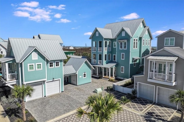 view of front of property featuring metal roof, a standing seam roof, an attached garage, and a balcony