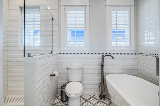 full bathroom with a soaking tub, tiled shower, tile walls, and toilet