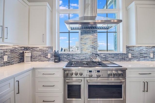 kitchen featuring range with two ovens, white cabinetry, decorative backsplash, light stone countertops, and island exhaust hood