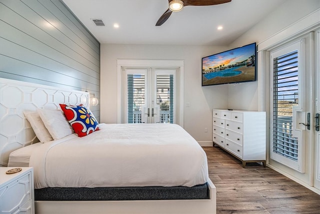 bedroom with access to exterior, french doors, multiple windows, and wood finished floors