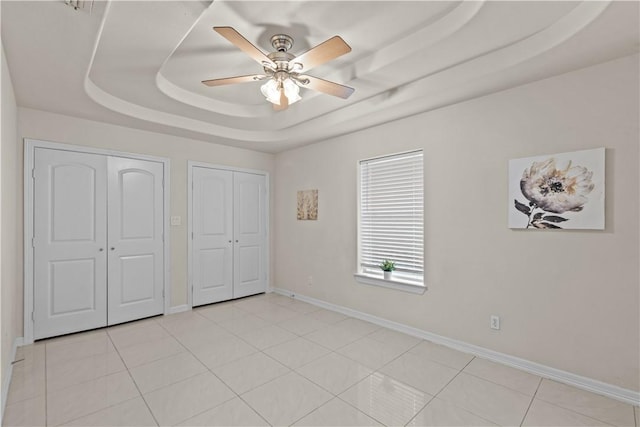 8230 Excalibur, Corpus Christi, TX 78414 - unfurnished bedroom featuring a tray ceiling, multiple closets, ceiling fan, and light tile patterned floors