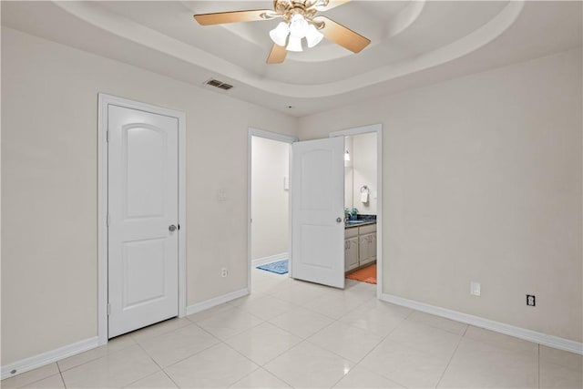 8230 Excalibur, Corpus Christi, TX 78414 - unfurnished bedroom with a raised ceiling, connected bathroom, ceiling fan, and light tile patterned flooring