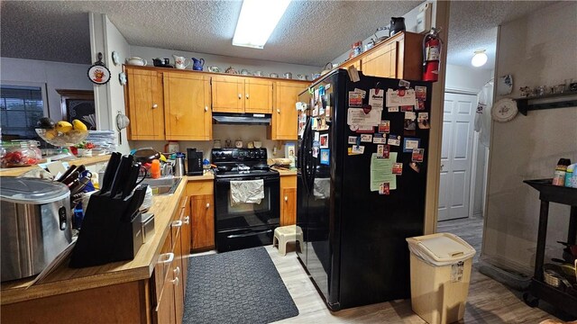 10200 Shane Dr, Corpus Christi, TX 78410 - kitchen with black appliances, under cabinet range hood, light countertops, a textured ceiling, and light wood-style floors