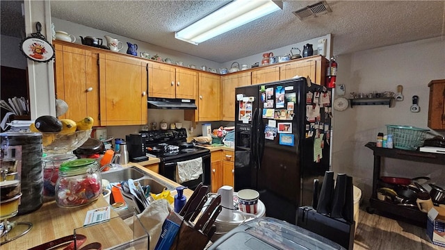 10200 Shane Dr, Corpus Christi, TX 78410 - kitchen with black appliances, under cabinet range hood, wood finished floors, a textured ceiling, and light countertops