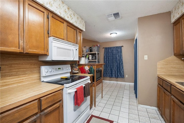 kitchen with brown cabinets, light countertops, white appliances, and visible vents