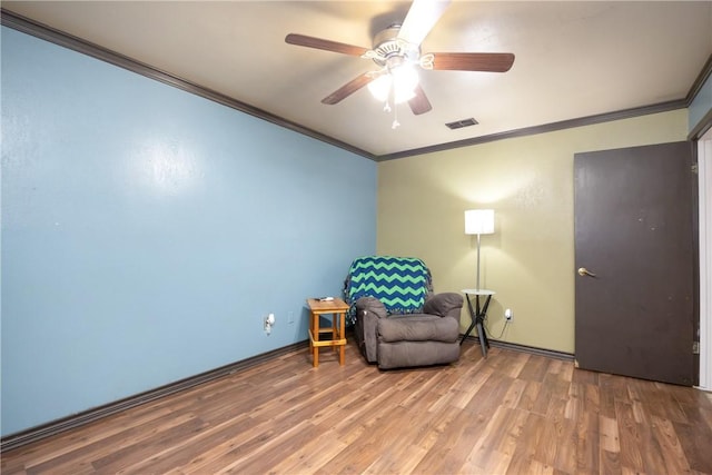 living area featuring ceiling fan, visible vents, wood finished floors, and ornamental molding