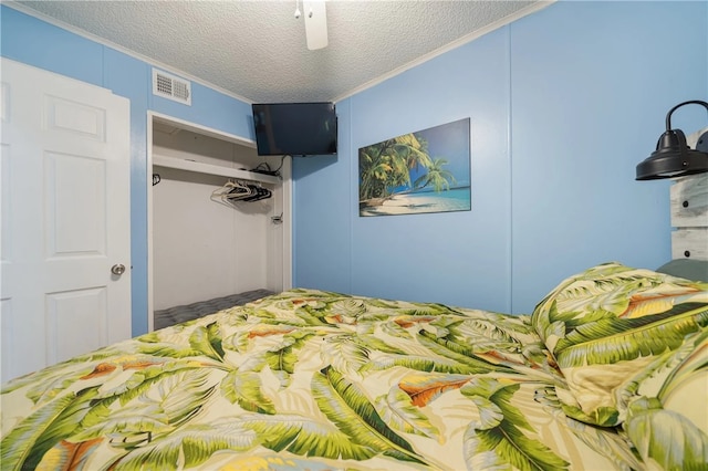 bedroom with ornamental molding, a closet, a textured ceiling, and ceiling fan