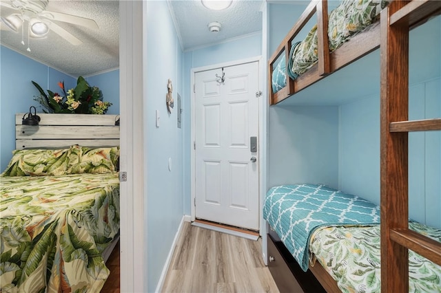 bedroom featuring a textured ceiling, ornamental molding, ceiling fan, a closet, and light hardwood / wood-style flooring