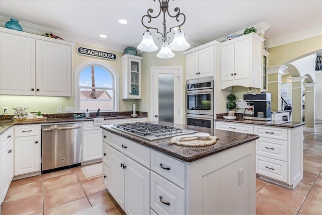 kitchen featuring ornamental molding, stainless steel appliances, a kitchen island, white cabinetry, and hanging light fixtures