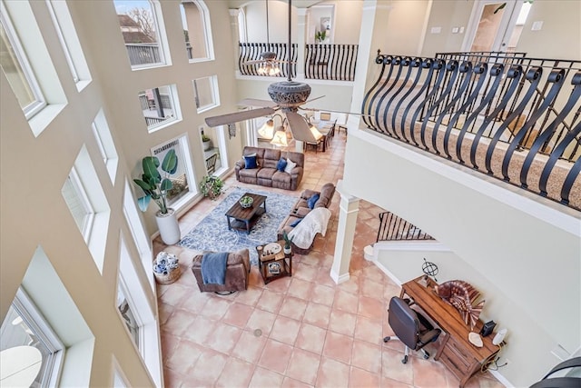 living room featuring ceiling fan, a high ceiling, and decorative columns