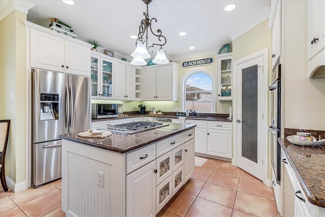 kitchen featuring stainless steel appliances, white cabinetry, dark stone counters, and a center island