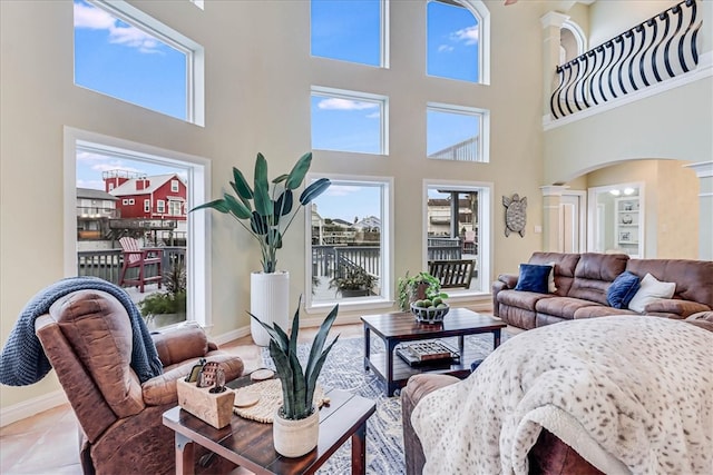 living room with a high ceiling, decorative columns, and light tile patterned flooring