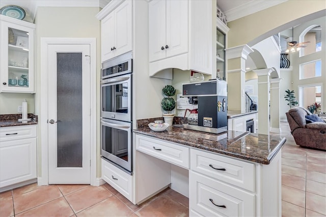 kitchen with white cabinets, light tile patterned floors, double oven, and decorative columns