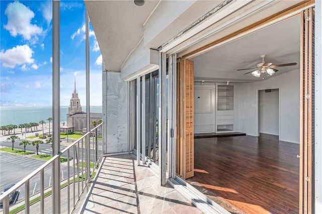 balcony featuring a water view and ceiling fan