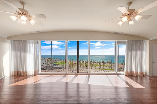 spare room featuring ceiling fan, wood-type flooring, vaulted ceiling, and a water view