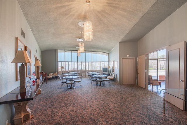 carpeted living room with high vaulted ceiling, a textured ceiling, and a notable chandelier