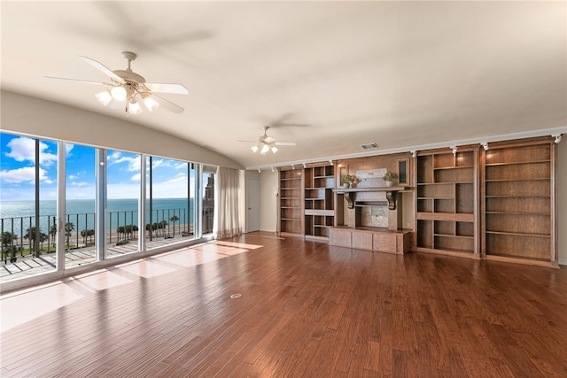 unfurnished living room featuring vaulted ceiling, a fireplace, hardwood / wood-style flooring, ceiling fan, and a water view