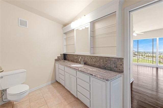 bathroom with vaulted ceiling, backsplash, vanity, ceiling fan, and toilet