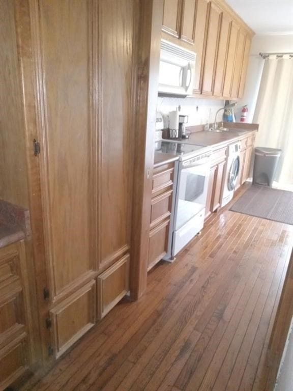 kitchen with hardwood / wood-style flooring, white appliances, washer / dryer, and sink