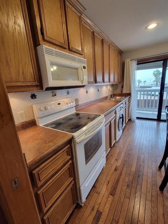 kitchen featuring white appliances, wood-type flooring, washer / dryer, and decorative backsplash