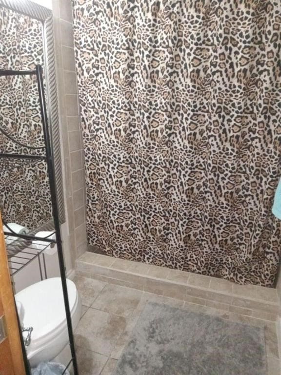 bathroom featuring a tile shower and toilet