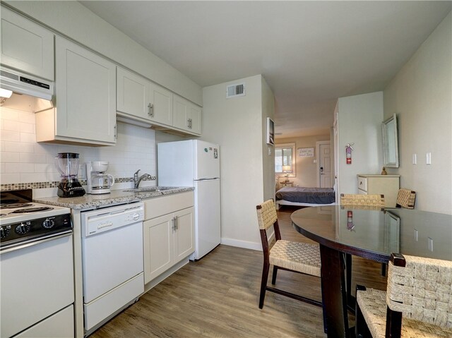 kitchen with white cabinets, light hardwood / wood-style floors, white appliances, and ventilation hood