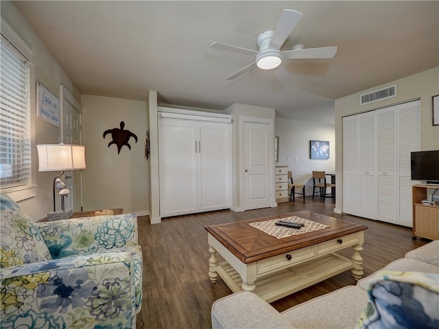 living room featuring ceiling fan and dark hardwood / wood-style floors