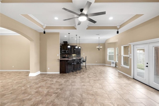 kitchen featuring baseboards, a kitchen bar, stainless steel microwave, open floor plan, and backsplash