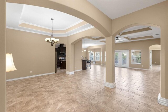 unfurnished room featuring a raised ceiling, ornamental molding, and ceiling fan with notable chandelier