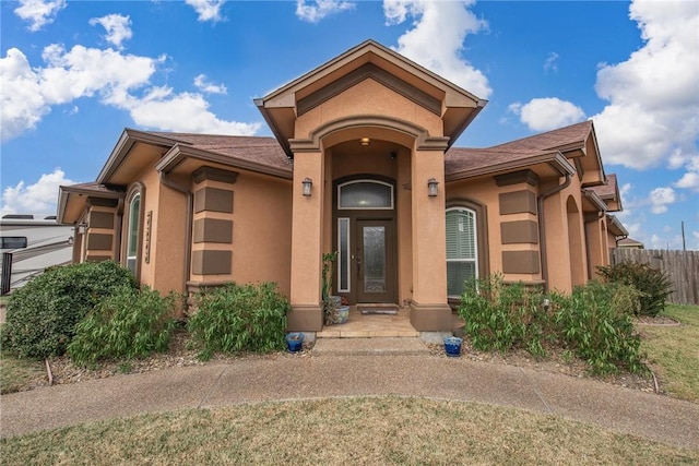 doorway to property with fence and stucco siding