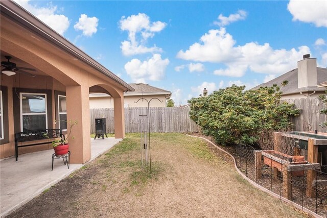 view of yard with a patio area, a ceiling fan, and fence