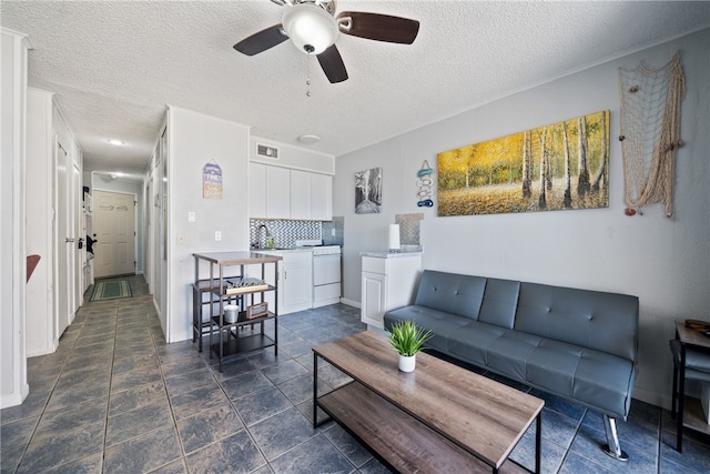 living room featuring washer / clothes dryer, a textured ceiling, and ceiling fan