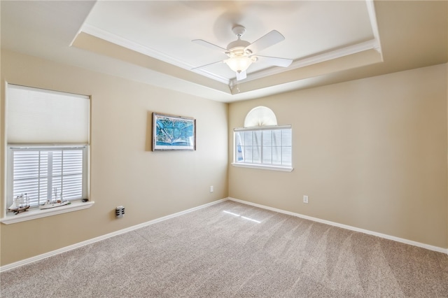 carpeted empty room with ceiling fan, a healthy amount of sunlight, crown molding, and a tray ceiling