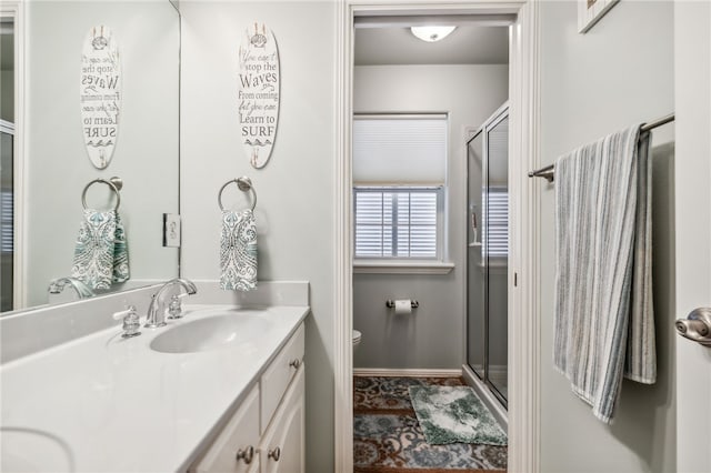 bathroom with vanity, toilet, and a shower with door