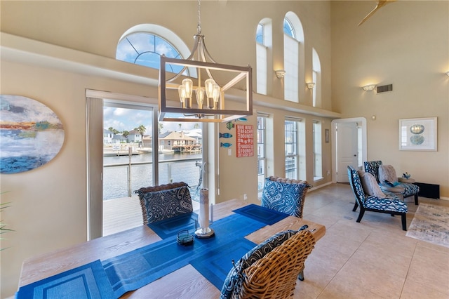 tiled dining area featuring a chandelier and a towering ceiling