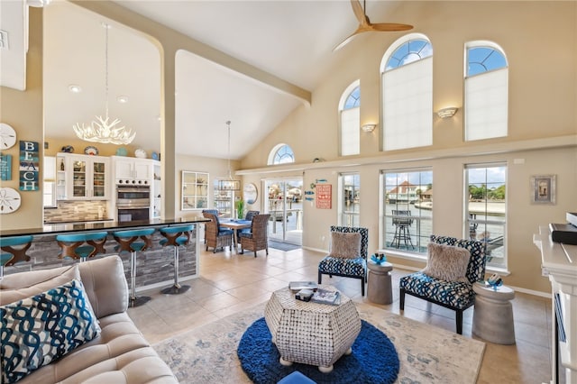 tiled living room featuring high vaulted ceiling, beamed ceiling, and ceiling fan with notable chandelier