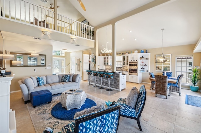 living room with high vaulted ceiling, a notable chandelier, and light tile patterned flooring