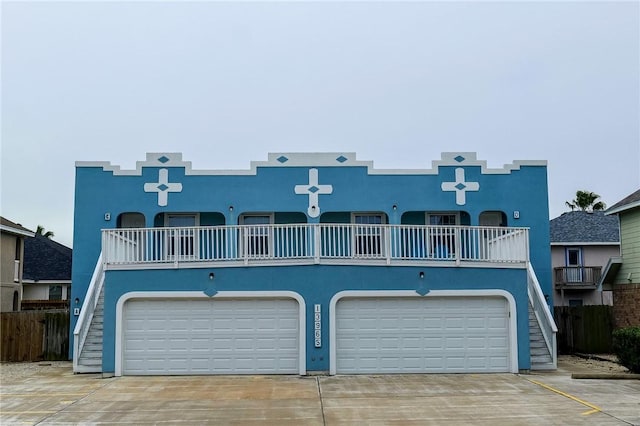 view of front of house with a garage, driveway, fence, and stucco siding