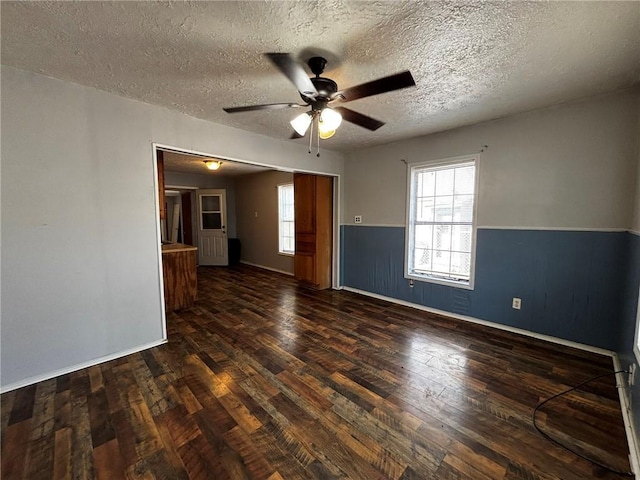 spare room featuring ceiling fan, plenty of natural light, a textured ceiling, and dark hardwood / wood-style flooring