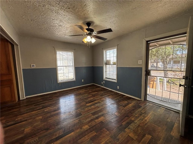 empty room featuring a textured ceiling, dark wood-type flooring, and ceiling fan