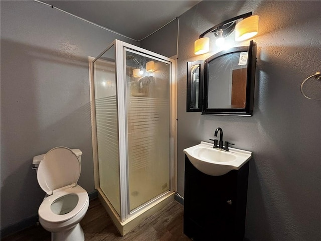 bathroom with vanity, a shower with shower door, toilet, and wood-type flooring