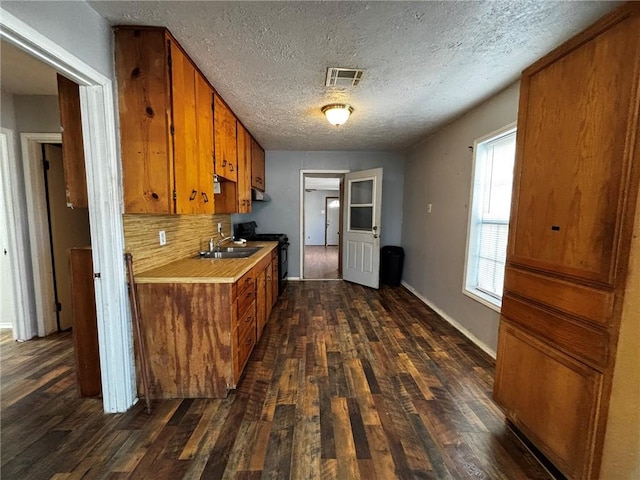 kitchen with sink, backsplash, dark hardwood / wood-style flooring, a textured ceiling, and black / electric stove