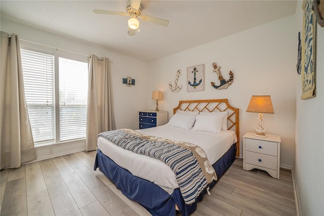 bedroom with light wood finished floors, a ceiling fan, and baseboards