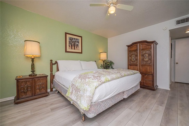 bedroom with light wood finished floors, baseboards, visible vents, and a ceiling fan