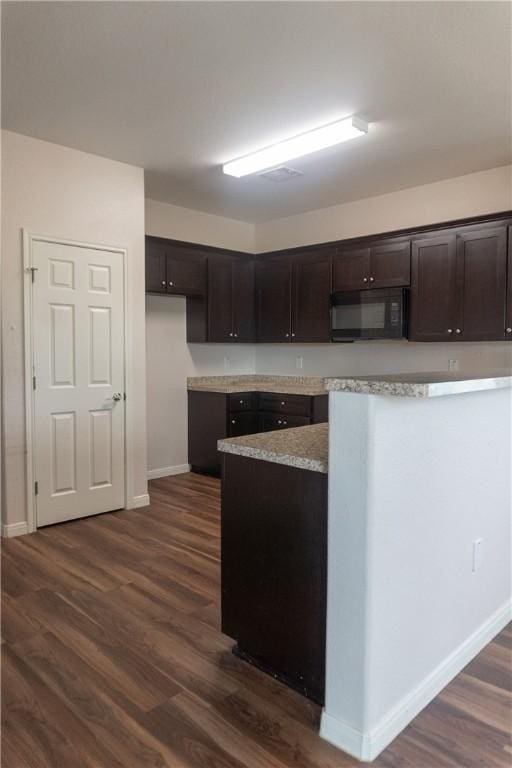 401 E Empresario St, Refugio, TX 78377 - kitchen featuring black microwave, dark brown cabinets, dark wood finished floors, baseboards, and light stone countertops