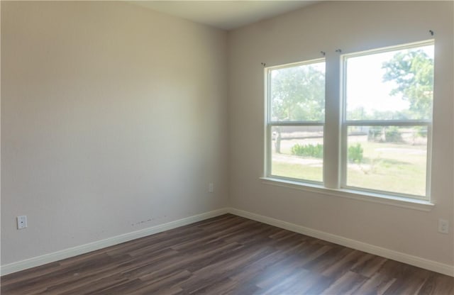 401 E Empresario St, Refugio, TX 78377 - spare room featuring dark wood-style flooring, plenty of natural light, and baseboards