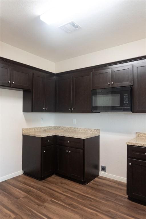 401 E Empresario St, Refugio, TX 78377 - kitchen with black microwave, dark brown cabinets, and baseboards