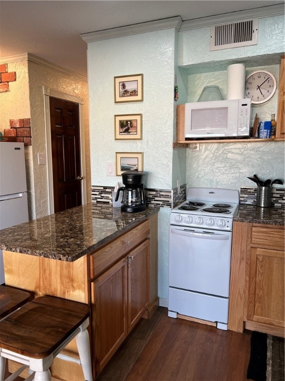 kitchen featuring white appliances, dark hardwood / wood-style floors, a breakfast bar, and ornamental molding